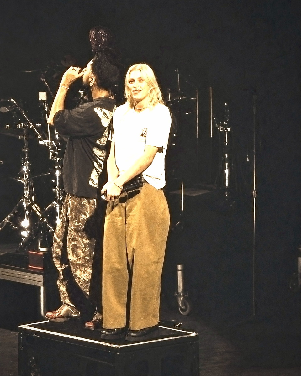 Backstage, one person adjusting another's hair before a performance