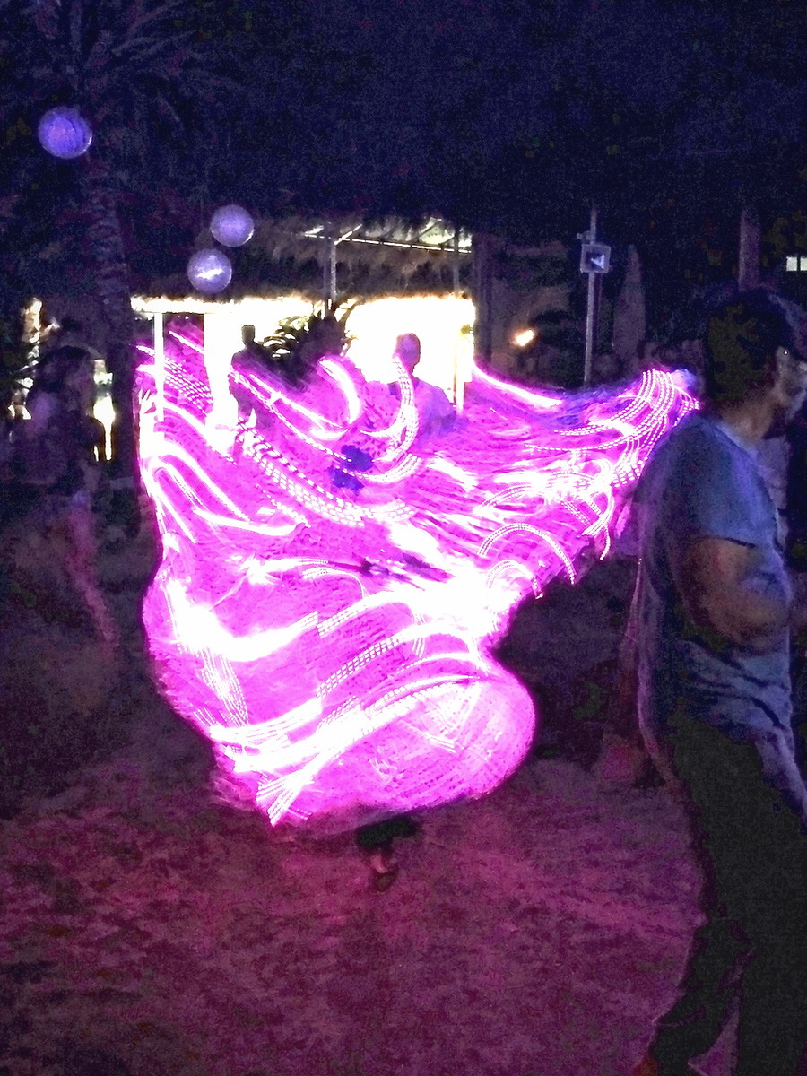 A performer alone at night in a costume trailing loops of light
