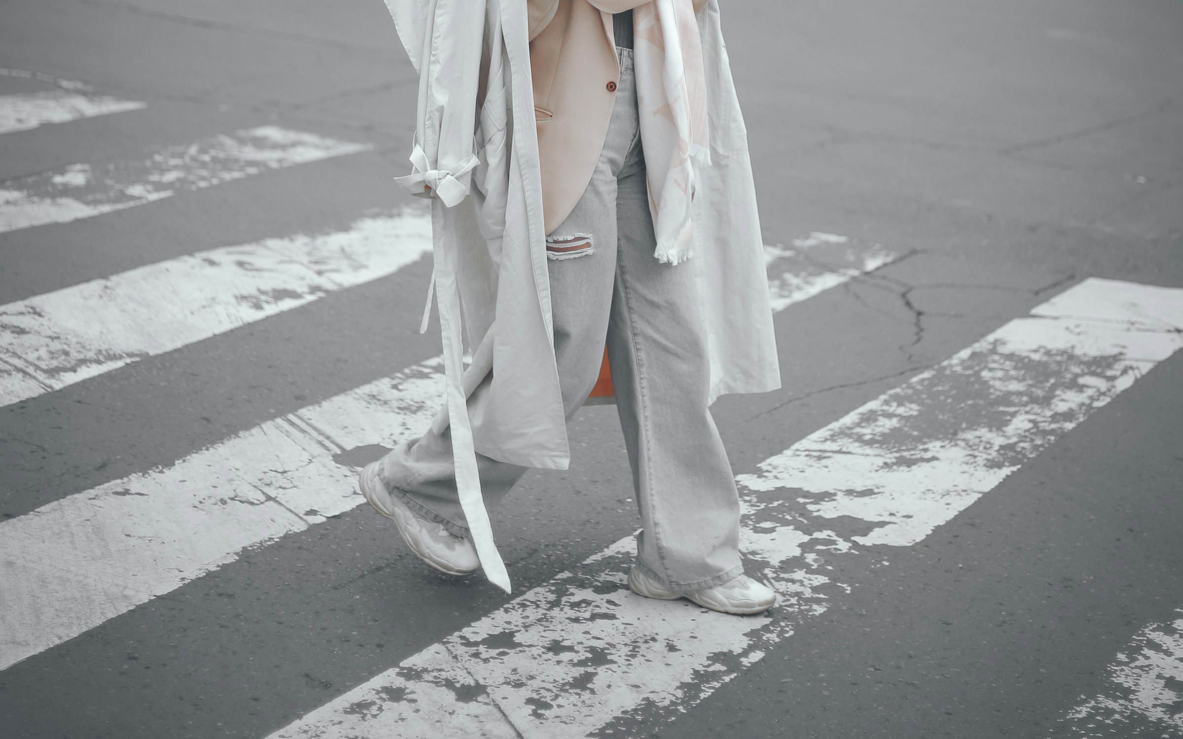 Oversized white layers and wide-leg denim, photographed mid-stride on a crosswalk