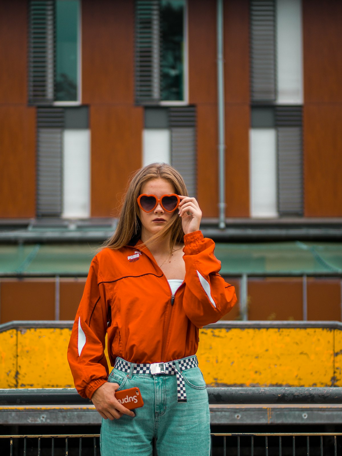 Orange track jacket, heart-shaped sunglasses, checkerboard belt